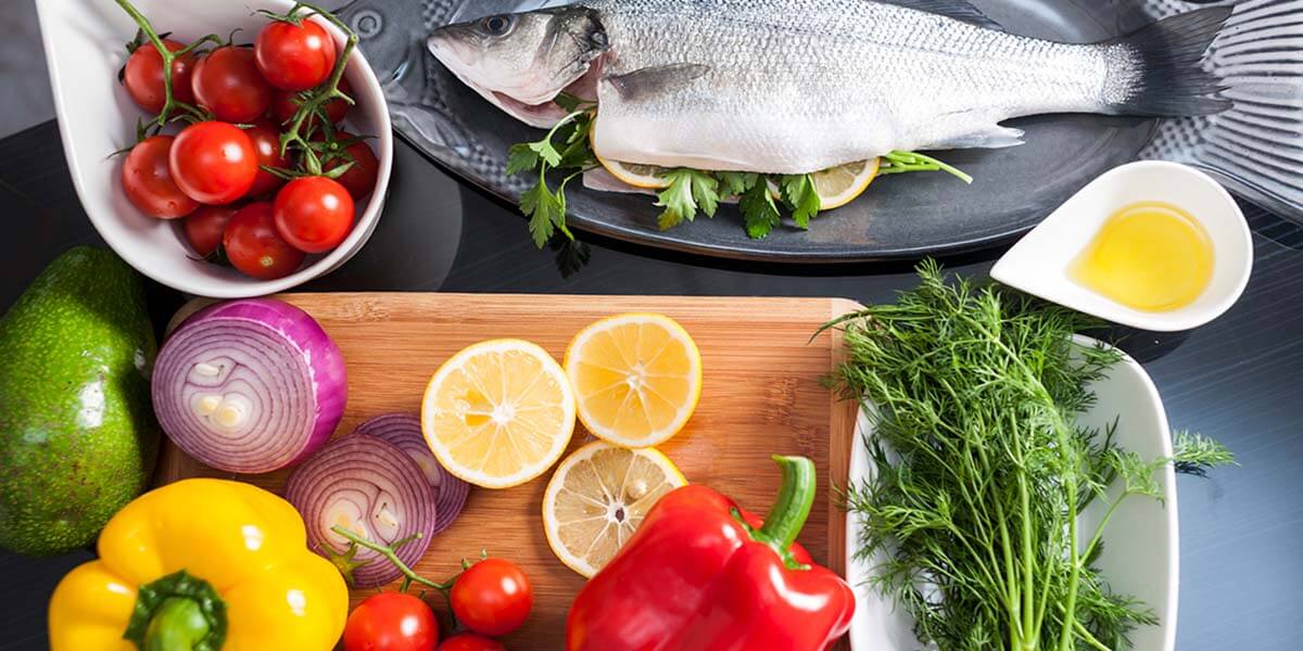 Potravinové doplnky: Ryba s citrónom, avokádom, olivovým olejom na drevenej doske